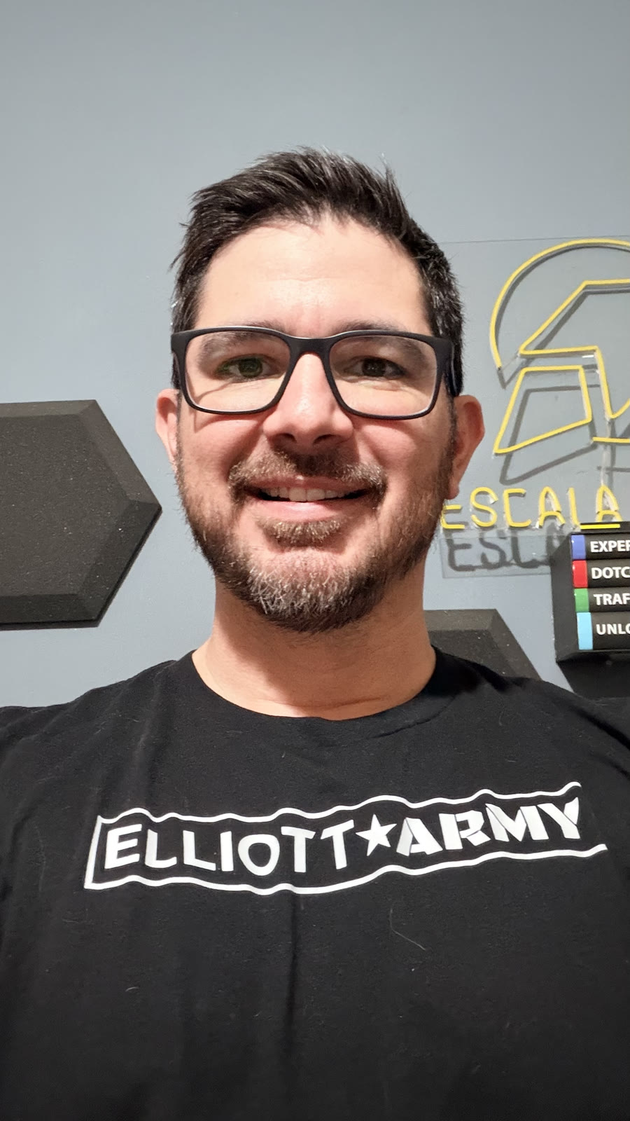 Carlos Barahona en su oficina, con lentes y barba, sonriendo a la cámara.